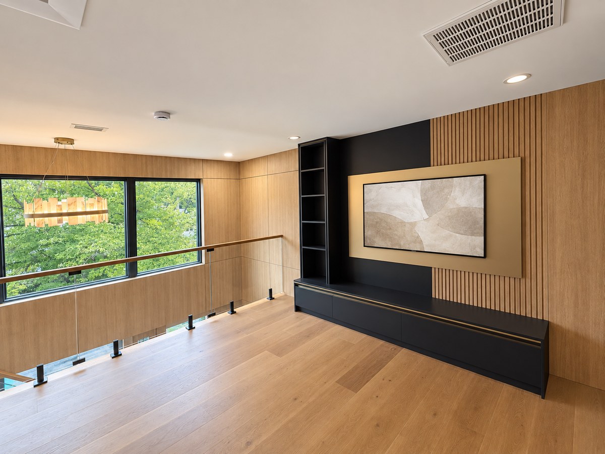 Finished media landing with oak paneling, built-in storage and wide windows