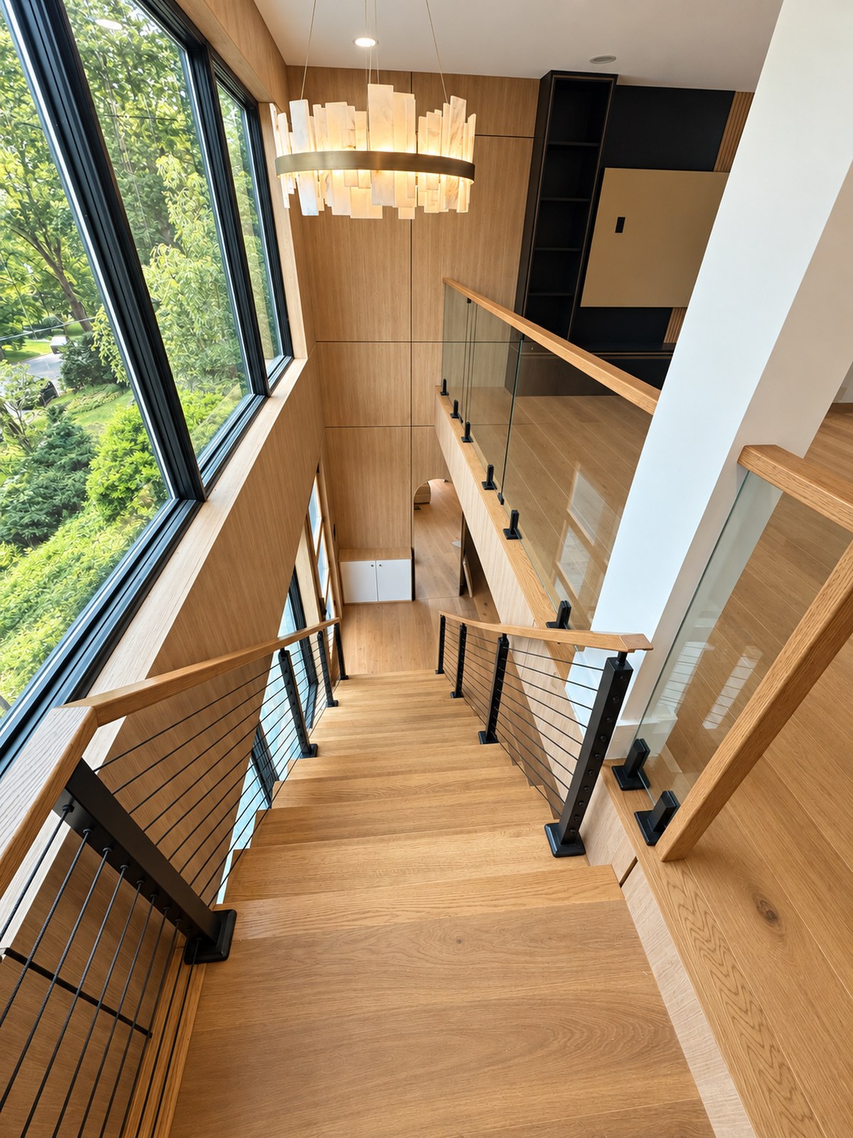 Custom oak staircase with glass railings and wood wall panels